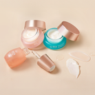 The MOCHI SKIN Instant Glow Travel Set by Fast Bundle features three skincare products in glass jars and a dropper bottle with rose gold lids, open to reveal cream and serum, displayed on a beige surface with product smears nearby.