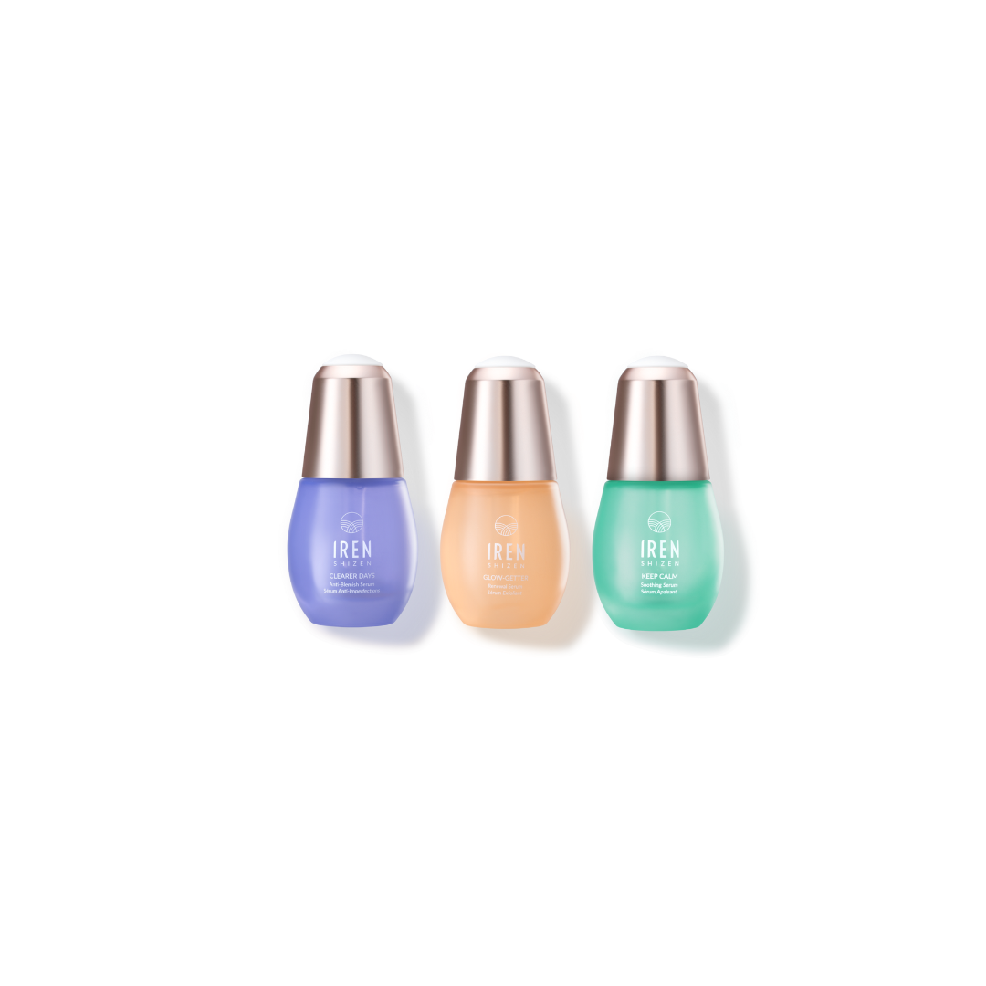 Three skincare serum bottles from IREN Shizen, including the CLEAR UP Anti-Blemish Set with purple, beige, and green colors, against a white background.