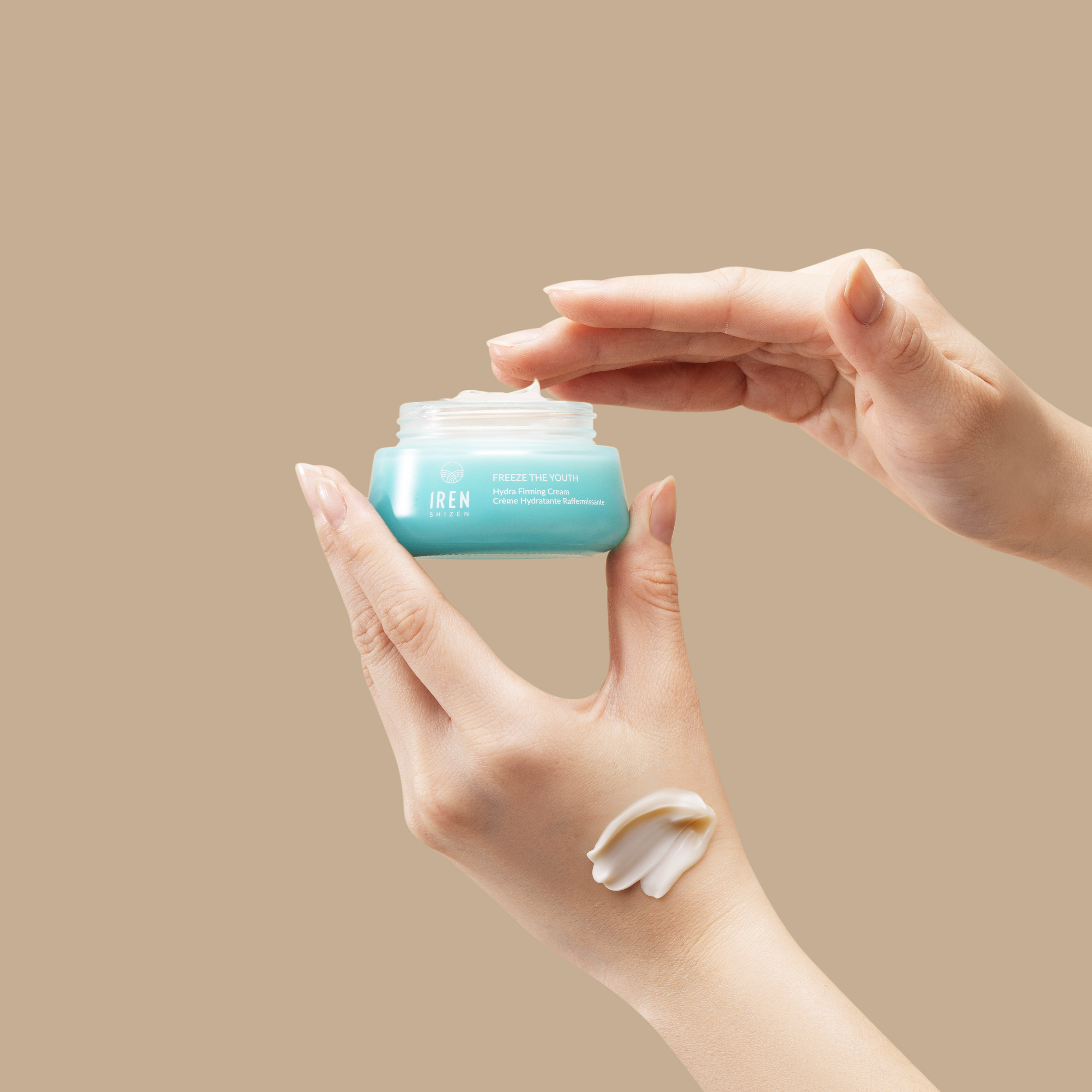 A person holding a jar of FREEZE THE YOUTH Hydra Firming Cream by IREN Shizen.