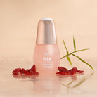 Close-up of the IREN Shizen APAC TIMELESS ELIXIR Anti-Aging Eye Skincare Kit bottle surrounded by dried red berries and a green leaf on a reflective surface with a beige background, showcasing the allure of anti-aging skincare.